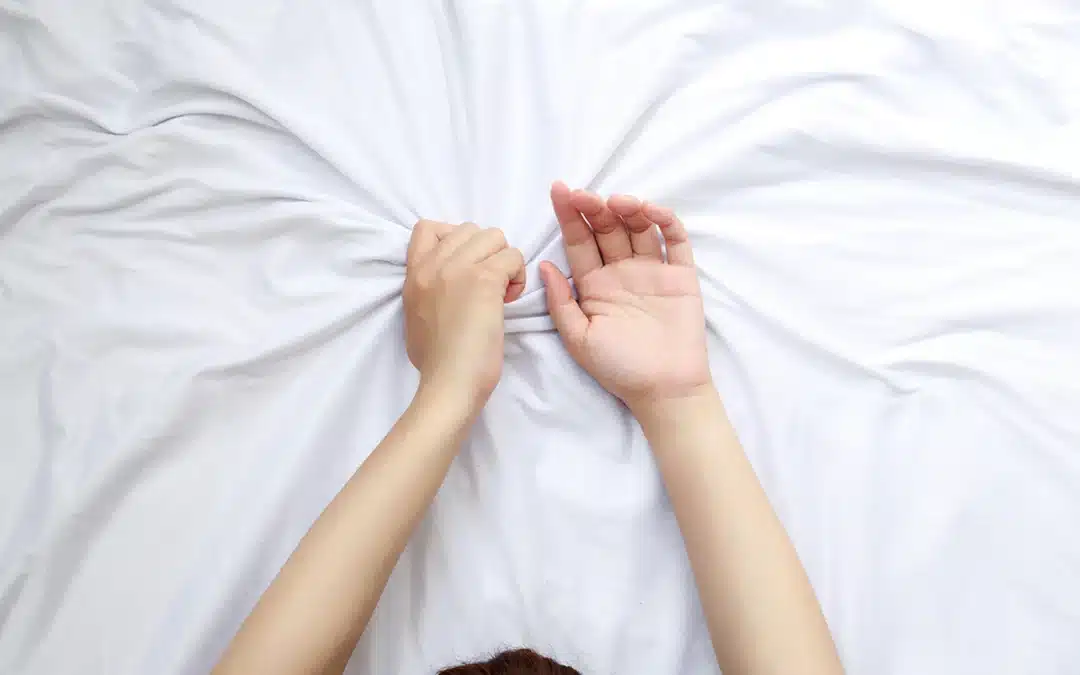 close up woman hands grasping the blanket in the moment of sexual pleasure