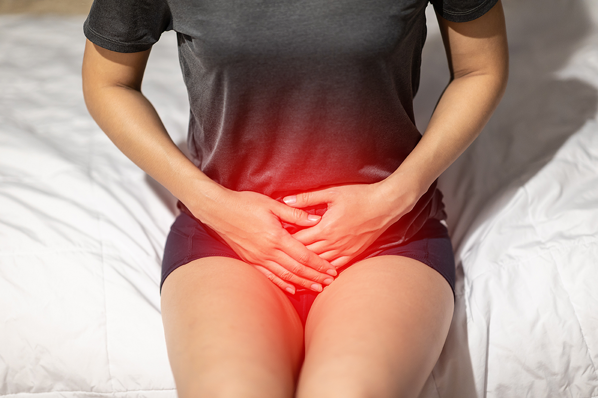 woman have mid section pain sitting on bed in bedroom
